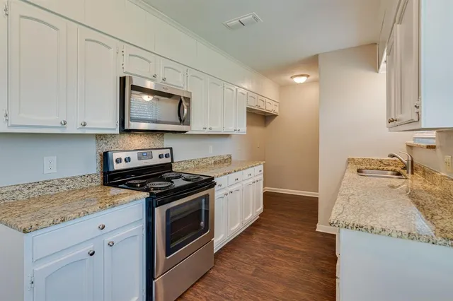 a kitchen with granite countertop wooden cabinets and a stove