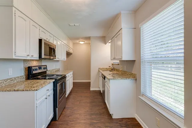 a kitchen with stainless steel appliances granite countertop a stove a sink and a microwave