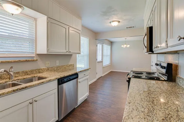 a kitchen with granite countertop a stove a sink and a refrigerator