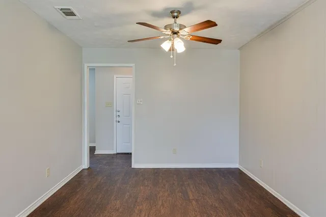 an empty room with wooden floor chandelier fan and window