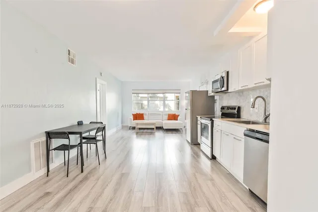 a kitchen with stainless steel appliances a stove a sink a refrigerator and wooden floor