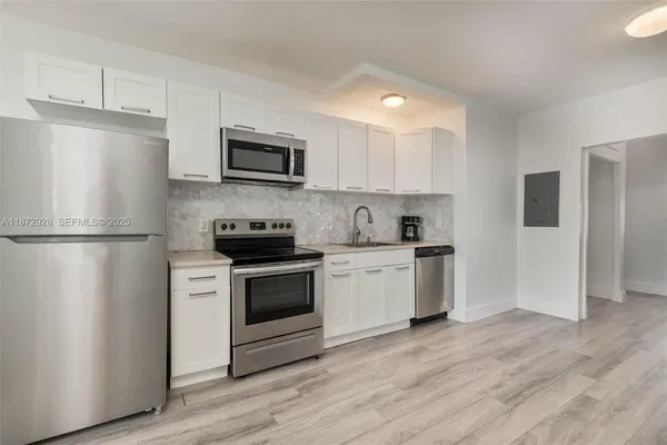 a kitchen with a refrigerator a stove top oven a sink and cabinets
