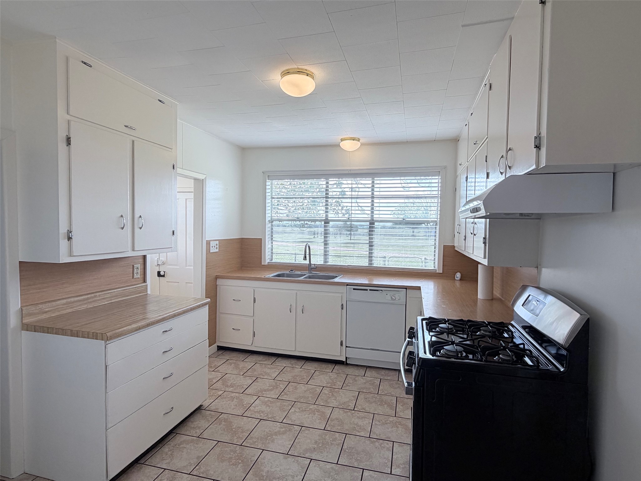 500 Greasy Bend Road Smithville, TX 78957 - Photo 5 of 21 Kitchen featuring extensive white cabinetry, tile flooring, dual basin sink, integrated dishwasher, and a gas range