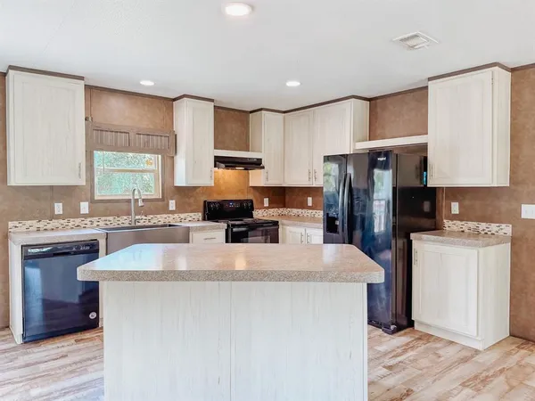 a kitchen with refrigerator a stove a sink cabinets and wooden floor