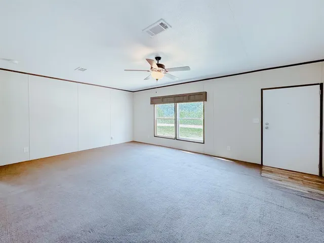 an empty room with windows and ceiling fan