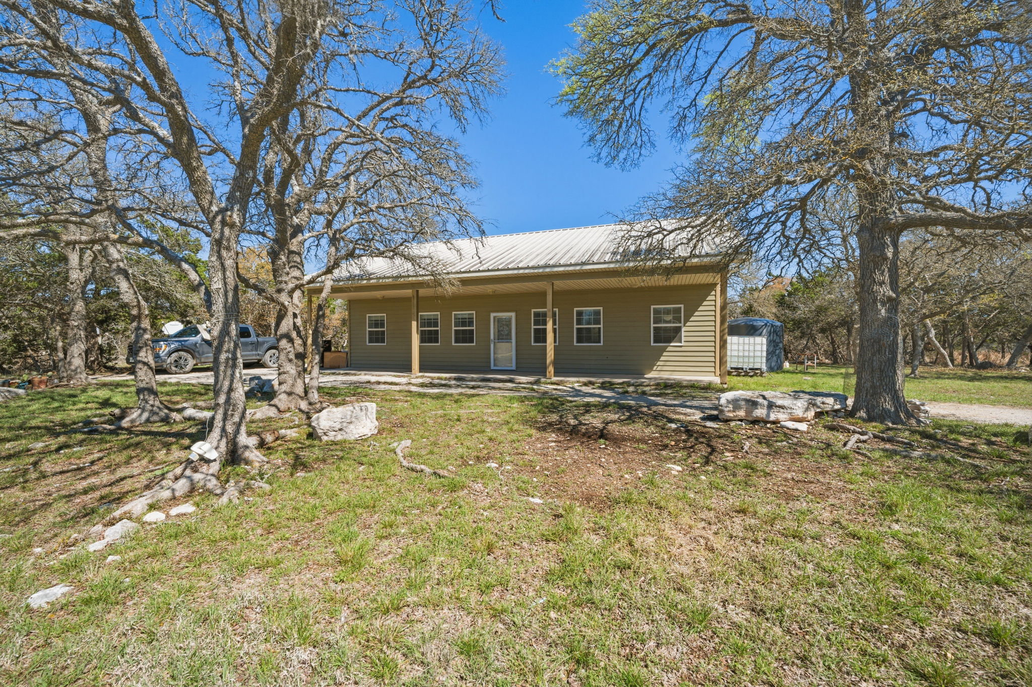 1301 Altwein Road Blanco, TX 78606 - Photo 28 of 40 Rear view of property featuring a metal roof, a lawn, and a patio