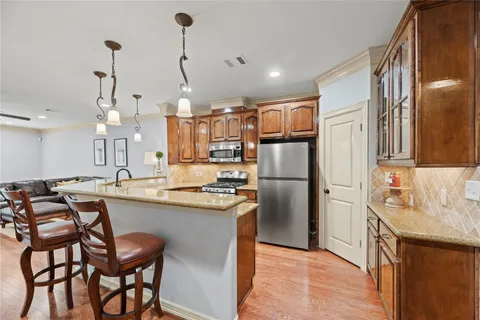 a kitchen with stainless steel appliances granite countertop a sink a stove a refrigerator and island with wooden floor