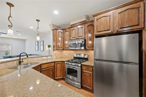 a kitchen with stainless steel appliances granite countertop a refrigerator a stove and a sink with cabinets