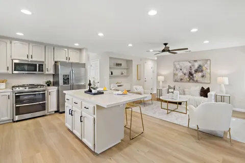 a kitchen with stainless steel appliances kitchen island wooden floors and white cabinets