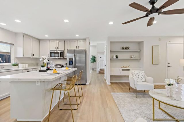 a large white kitchen with granite countertop a stove and a wooden floors