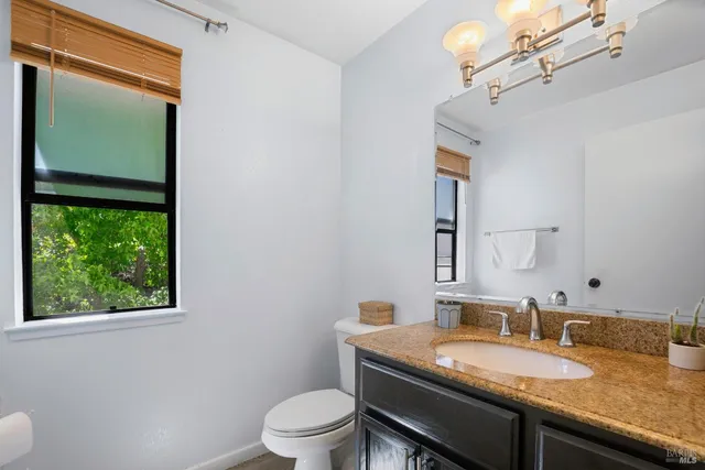 a bathroom with a granite countertop sink a toilet and mirror