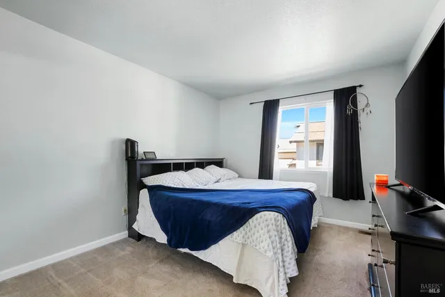 a bedroom with a bed and a flat tv screen on a dresser