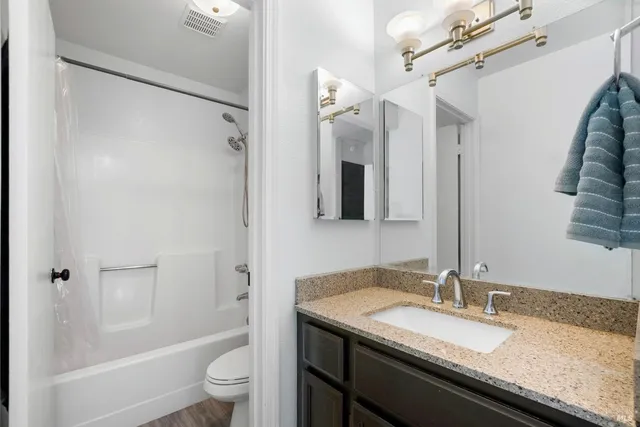 a bathroom with a granite countertop sink toilet and shower