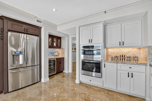 a kitchen with stainless steel appliances granite countertop a stove top oven a refrigerator a sink and a island