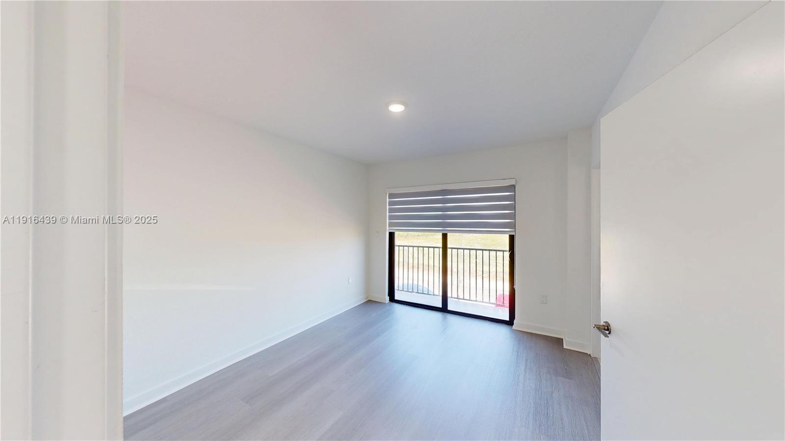 14546 Southwest 260th Street, Unit 14546 Homestead, FL 33032 - Photo 17 of 31 a view of an empty room with a window and wooden floor