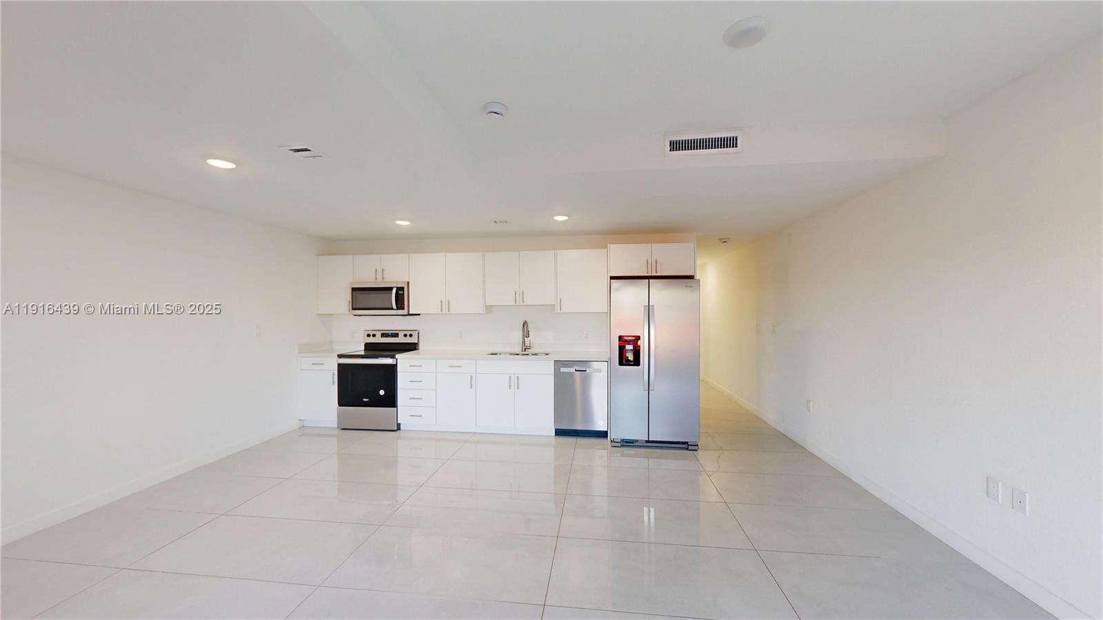14546 Southwest 260th Street, Unit 14546 Homestead, FL 33032 - Photo 3 of 31 a view of a kitchen with a sink and dishwasher a refrigerator with white cabinets