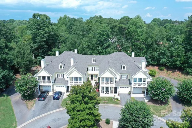 an aerial view of house with yard and trees all around