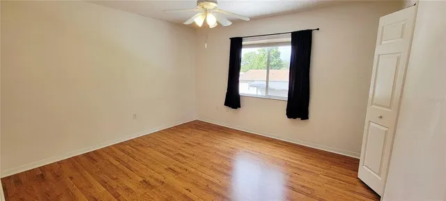 a view of an empty room with wooden floor and a window