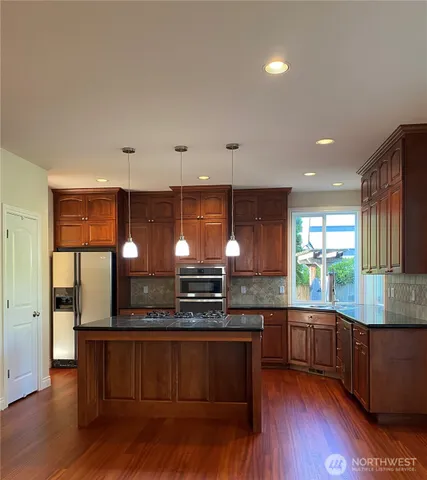 a kitchen with stainless steel appliances granite countertop wooden floors and sink