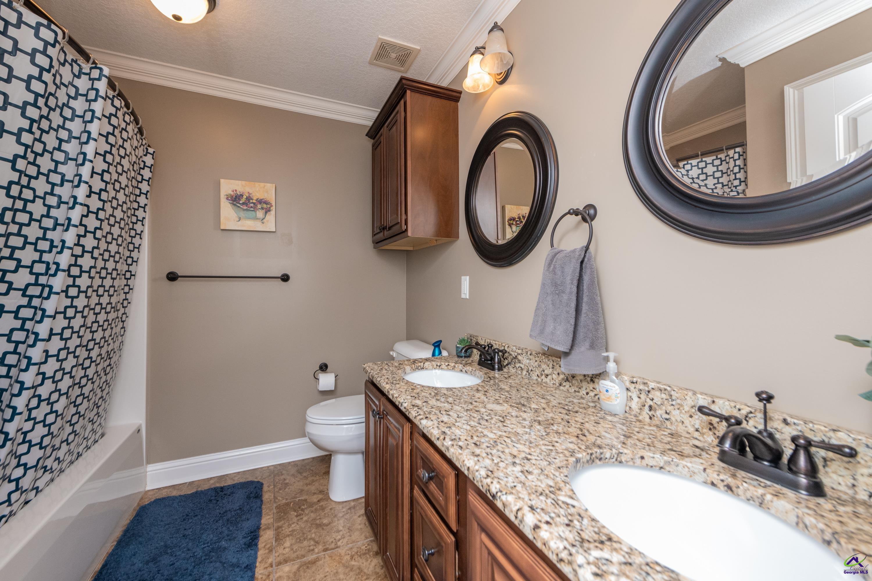 405 Old Bridge Road Warner Robins, GA 31088 - Photo 48 of 58 a bathroom with a granite countertop toilet a sink and a mirror