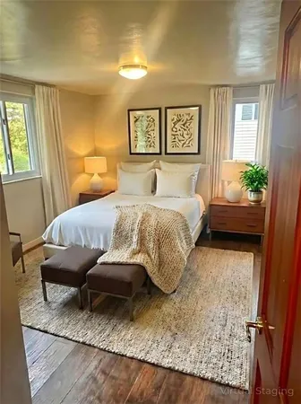 a bedroom with a bed painting on wall and a potted plant