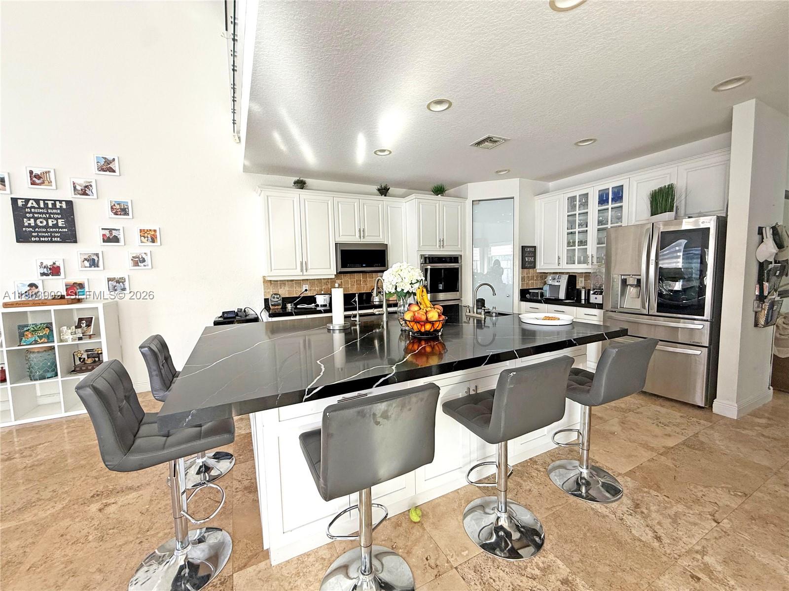 18560 Southwest 44th Street Miramar, FL 33029 - Photo 6 of 16 a kitchen with stainless steel appliances granite countertop a sink a stove a refrigerator cabinets and chairs