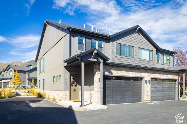 1141 520 West Midway, UT 84049 - Photo 30 of 40 Contemporary residence featuring a covered entry, stone facade accents, two garage doors, and dark gray siding