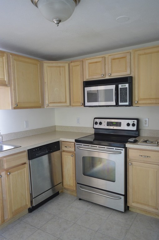 222 Stackpole Street, Unit 15 Lowell, MA 01852 - Photo 8 of 16 a kitchen with granite countertop a stove top oven microwave and cabinets