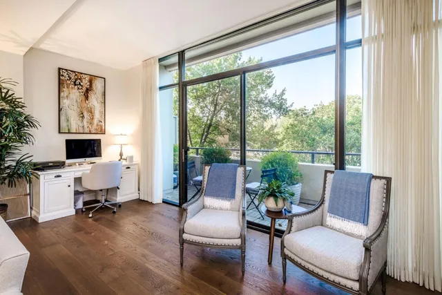 a living room with furniture floor to ceiling window and wooden floor