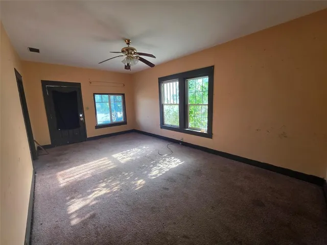 an empty room with windows and ceiling fan