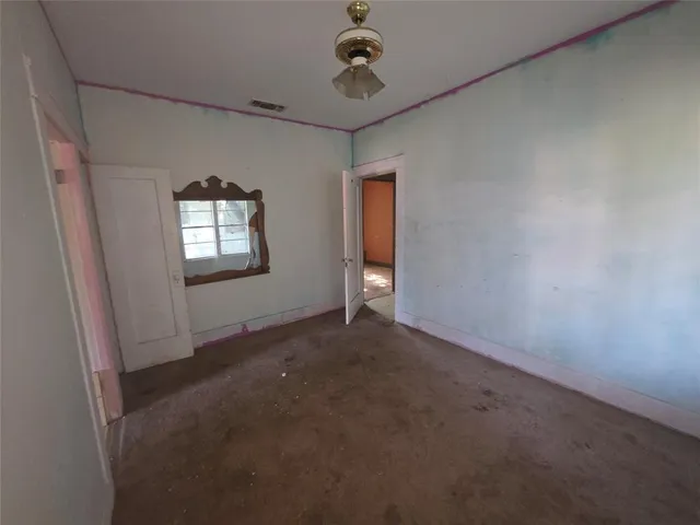 an empty room with windows and ceiling fan