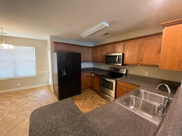 a kitchen with granite countertop a refrigerator and a stove top oven