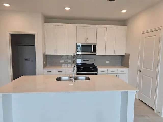 a kitchen with granite countertop a refrigerator sink and white cabinets