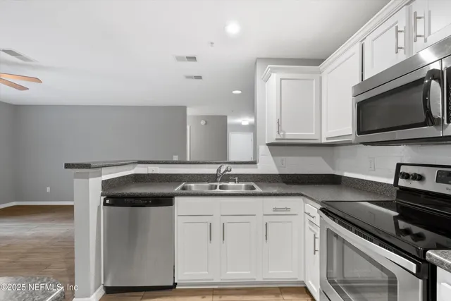 a kitchen with stainless steel appliances granite countertop a sink stove and microwave