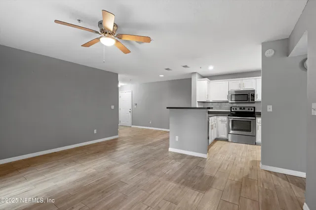 a kitchen with granite countertop a refrigerator oven a sink and dishwasher with wooden floor