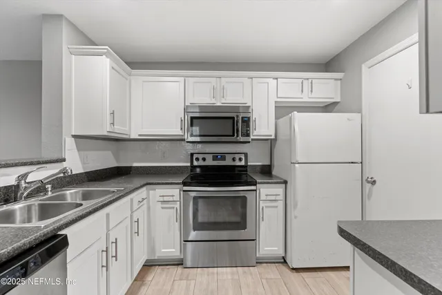 a kitchen with white cabinets and stainless steel appliances