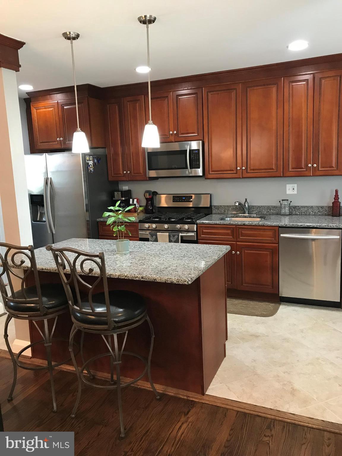 223 Westowne Road Baltimore, MD 21229 - Photo 9 of 21 a kitchen with stainless steel appliances granite countertop a sink a stove a microwave a refrigerator and chairs