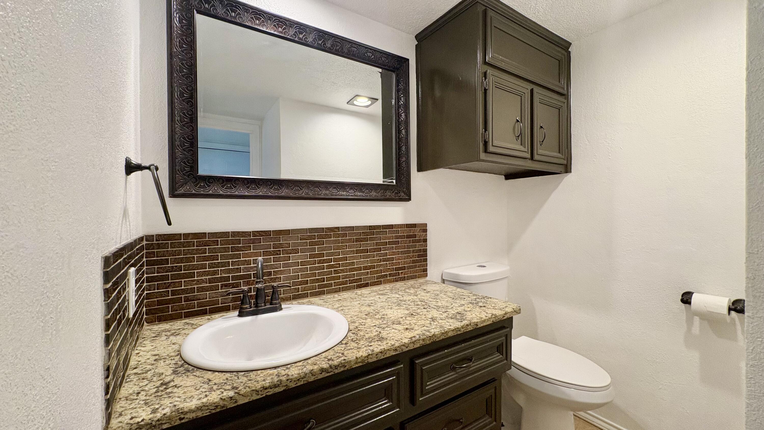 502 North Homestead Avenue Lubbock, TX 79416 - Photo 19 of 33 a bathroom with a granite countertop toilet sink and mirror