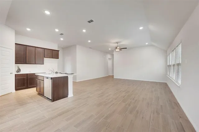 a large kitchen with a large counter top a sink stainless steel appliances and cabinets