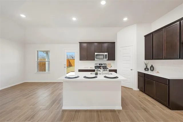 a kitchen with stainless steel appliances kitchen island granite countertop a sink stove and microwave