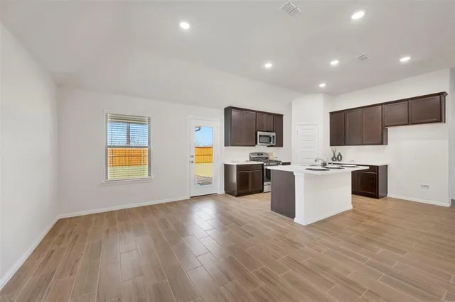 a large kitchen with a wooden floor and stainless steel appliances
