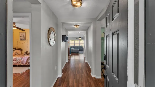 a view of a hallway with wooden floor and a living room