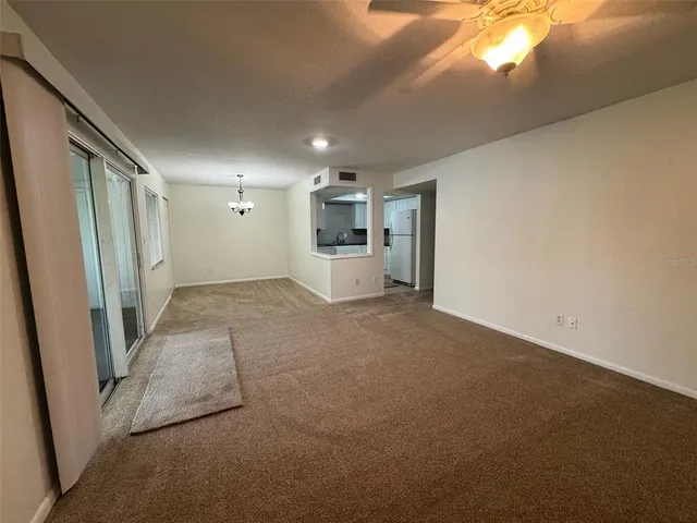 an empty room with a chandelier fan and windows