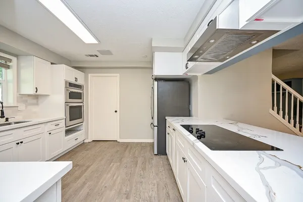 a kitchen with granite countertop a sink and dishwasher a stove top oven with wooden floor