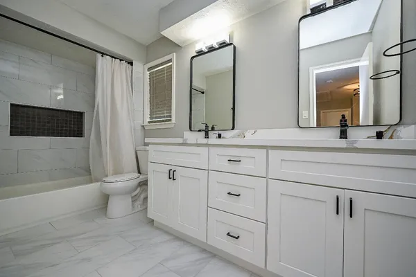 a bathroom with a double vanity sink toilet mirror and bathtub