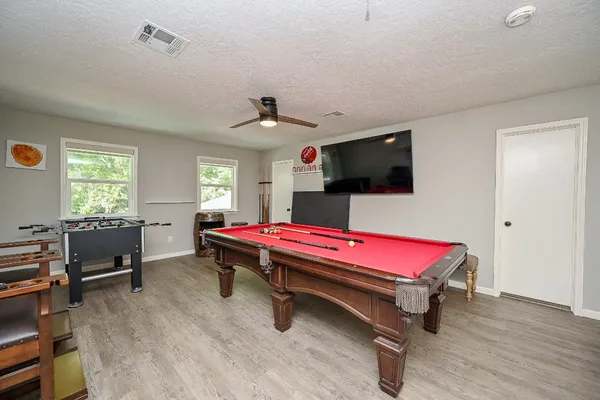 a living room with furniture pool table flat screen tv and windows