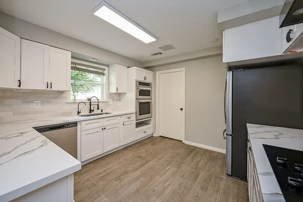 a kitchen with granite countertop a stove a sink and a refrigerator