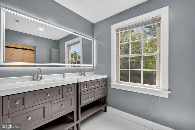 a en suite bathroom with a granite countertop double vanity sink a window and a mirror