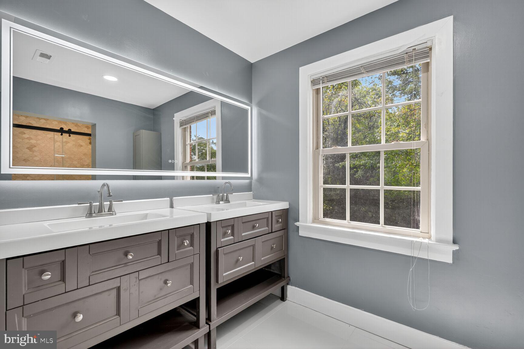 3612 Swann Road Suitland, MD 20746 - Photo 12 of 30 a en suite bathroom with a granite countertop double vanity sink a window and a mirror