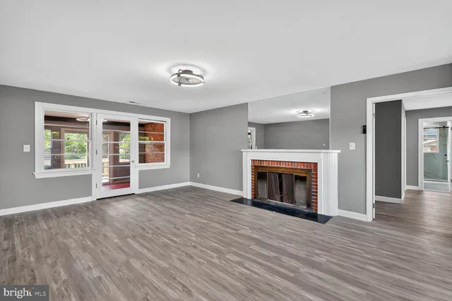 an empty room with wooden floor fireplace and windows